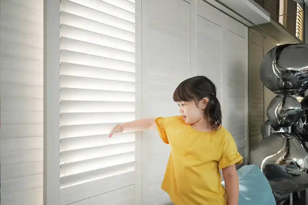 ウッドシャッターに手を差し込む女の子とキッズデザイン賞のロゴ