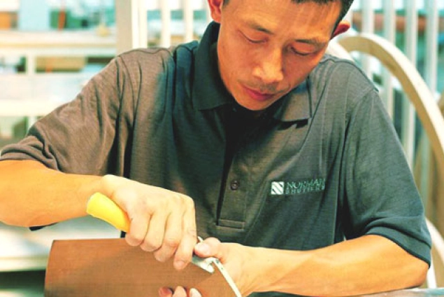男性が道具を使い木材を加工している