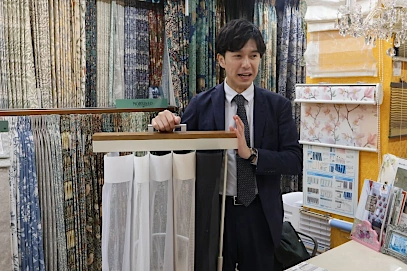 スマートドレープシェードのサンプルを用いて製品説明をするビジネスマン