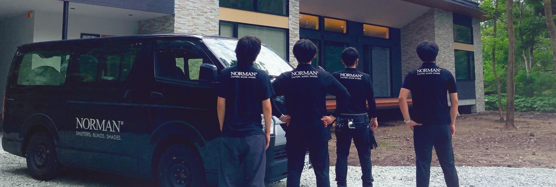 ノーマンジャパン採用ページ キービジュアル（PC用1枚目）施工チーム4人の男性スタッフのバックショットと社名入りワゴン車