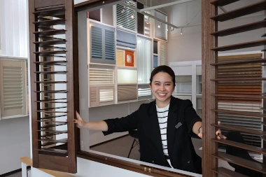 ショールーム　M・Kさんのプロフィール写真。ウッドシャッターを開いて笑顔を向ける女性。