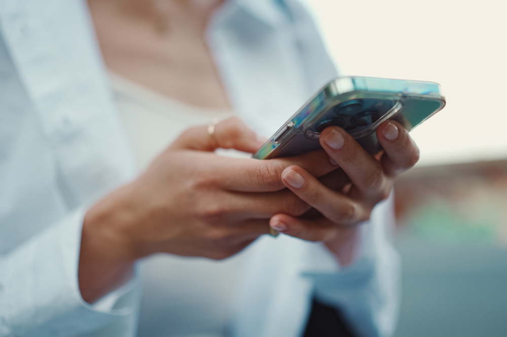 スマートフォンに搭載したShadeAutoアプリを屋外で操作している女性