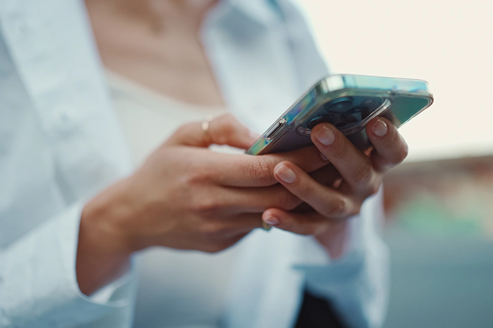 屋外でスマートフォンでスクリーンを操作している女性