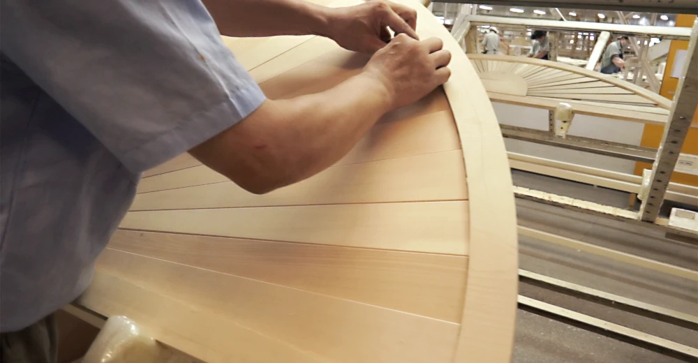 工場で円形のウッドシャッターを組み立てる男性