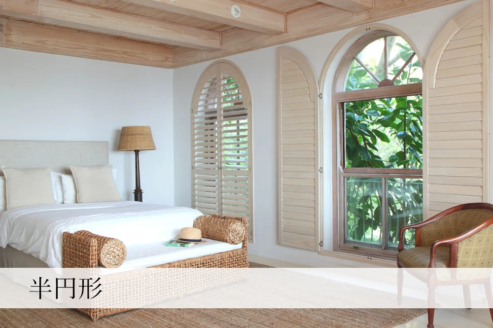 リゾートスタイルの寝室にある半円形窓に、ウッドシャッターを導入した事例