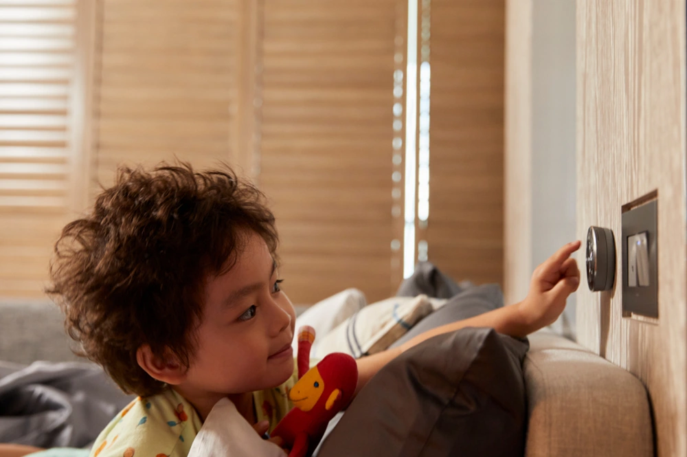 ベッドルームの壁に掛けられたSmartDial™を操作する男の子