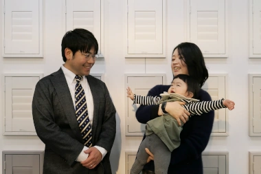パパママのプロフィール写真。ウッドシャッターの前で大人2人と幼児が笑みを見せている。