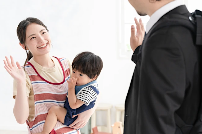 保育園で男児を預けてお別れのあいさつをするパパと保育士（イメージ画像）