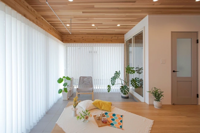 北欧風家具や観葉植物があるリビングにスマートドレープシェードがある様子